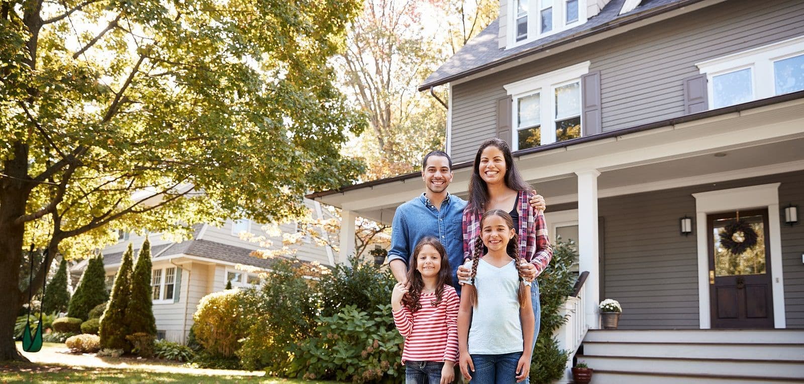 portrait of smiling family in front of home